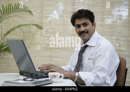 Portrait of a businessman working on laptop in an office and smiling Stock Photo