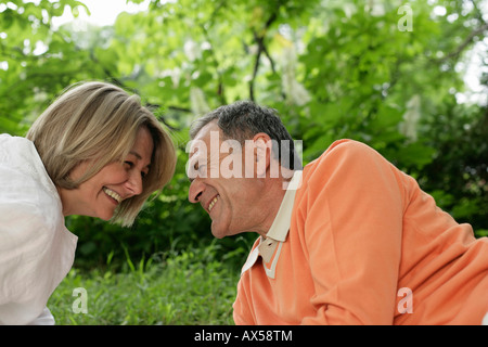 Laughing mature couple lying on grass and looking into each other's eyes Stock Photo
