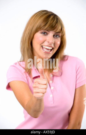 Young woman with thumbs up, smiling, close-up Stock Photo