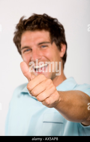 Young man showing thumbs up, focus on thumb, portrait Stock Photo