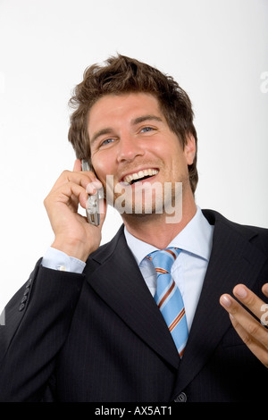 Young businessman using mobile phone, smiling, close-up Stock Photo