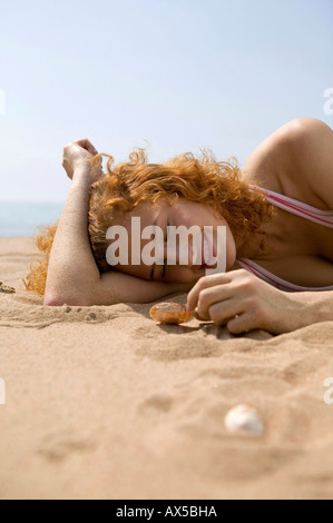 Young woman on beach, holding shell Stock Photo