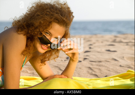 Young woman wearing sun glasses, relaxing on beach Stock Photo