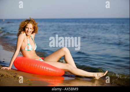 Young woman on beach with floating tyre Stock Photo