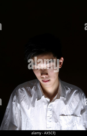 Young man in mystical illumination looking down Stock Photo