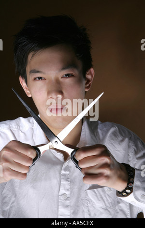 Young man holding opened scissors Stock Photo