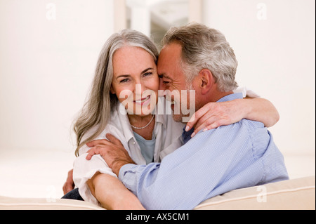 Mature couple embracing on sofa, smiling Stock Photo