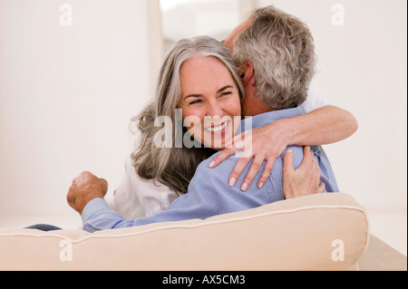 Mature couple embracing on sofa, smiling Stock Photo