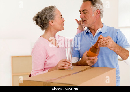 Mature couple holding champagne bottle and glass, close-up Stock Photo