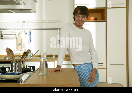 Young man standing in kitchen, smiling, portrait Stock Photo