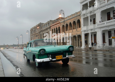 Green vintage car driving down a street on a rainy day at the Malecón, Havana, Cuba, Caribbean Stock Photo