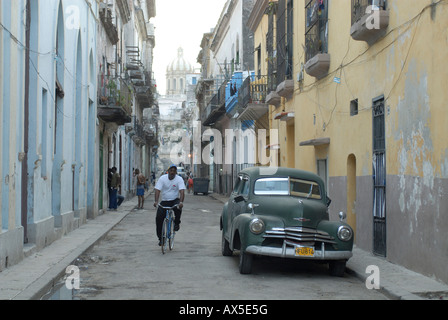 Vintage car and cyclist in an alley in the old part of Havana, Cuba, Caribbean Stock Photo