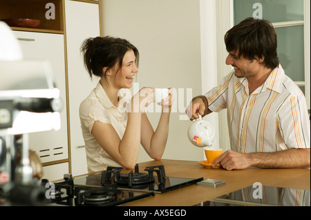 Young couple in kitchen, drinking tea, smiling Stock Photo