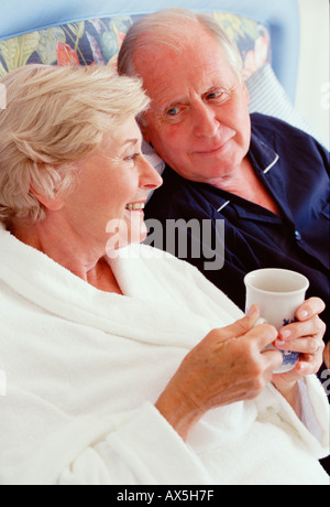Retired couple indoors in bathrobes. Relaxing with hot drink. Stock Photo