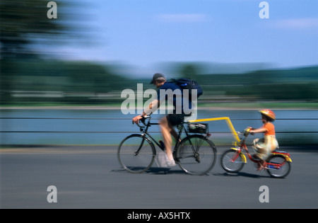 Cyclist and girl wearing bicycle helmet cycling Stock Photo