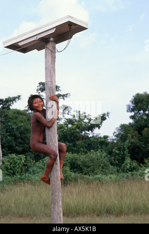 A-Ukre Village, Xingu, Brazil. Kayapo girl climbing pole which supports a solar panel power for medical post fridge. Stock Photo