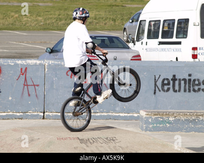 Young boy doing a wheelie on a BMX in skate park Stock Photo