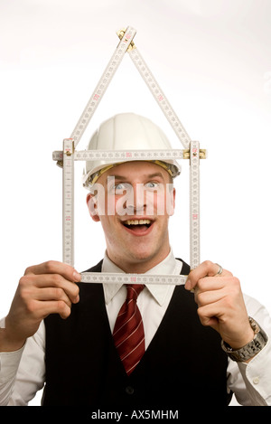 Man dressed in suit holding yardstick shaped into a house Stock Photo
