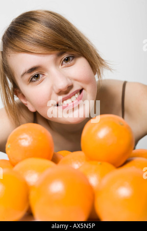 Many oranges in front of a laughing young woman Stock Photo