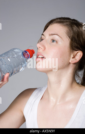 Young woman drinking from a bottle of water during workout Stock Photo