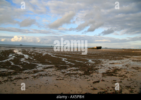 The beach at Arromanches Normandy with a stranded section of the Mulberry Harbour (spud pier) stuck on the beach. Stock Photo