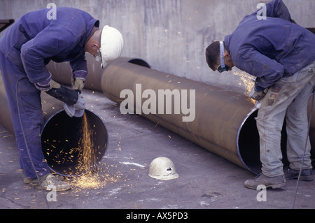 Pocerady, Czech Republic. Workers using angle grinders to clean the ends of steel pipes for welding at the power station. Stock Photo