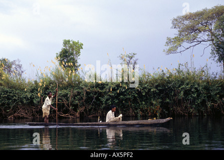 Zambia. Zambian woman in a dug out canoe reading with man polling the canoe. Stock Photo