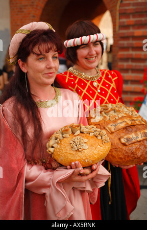 Girls dressed in traditional costumes showing decorated bread, Folklore Days in Olsztyn, Poland Stock Photo