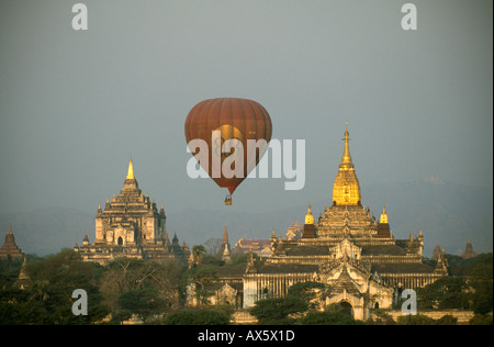 Hot air balloon at sunrise passing behind Ananda temple (right) in Bagan, Myanmar Stock Photo