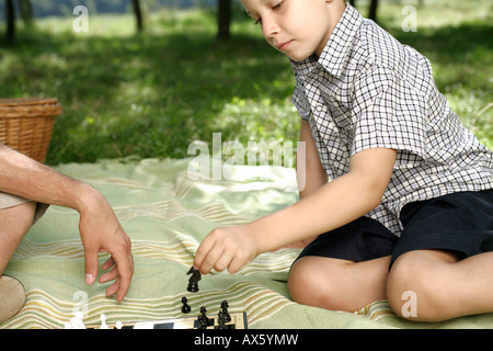 Father and son playing chess on a blanket Stock Photo