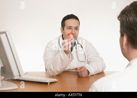 Physician with stethoscope handing bottle of pills to a patient Stock Photo