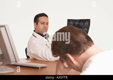 Physician with stethoscope showing CT scan image, delivering diagnosis to patient Stock Photo