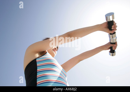 Low angle view of a young woman holding two dumbbells Stock Photo