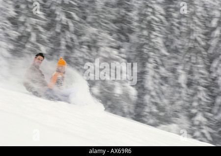 Young couple sliding on sledge, side view Stock Photo