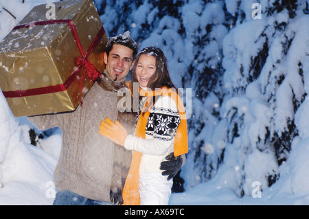 Man pulling woman holding present on sledge, side view Stock Photo