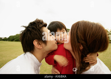 A couple kiss their son amidst a vast ground Stock Photo