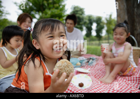A girl having lunch by the trees with her family Stock Photo