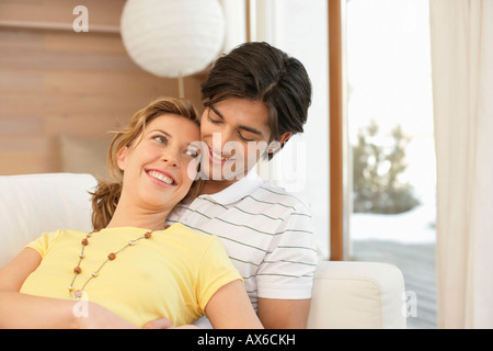 Smiling young couple sitting on a sofa Stock Photo