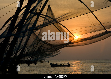 Fishing Boat and Chinese Fishing Nets at Sunset in Cochin India Stock Photo