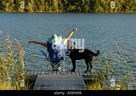 Rear view of woman sitting in armchair on pier with dog Stock Photo