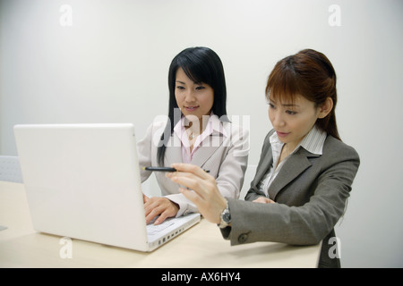 Two businesswomen working on the laptop together Stock Photo