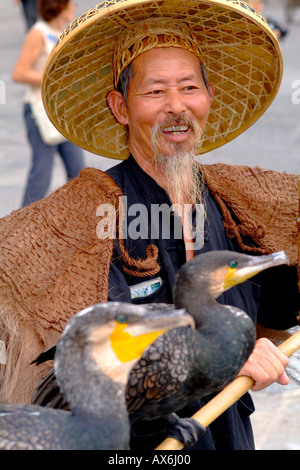 Old man fisherman with his cormorant fishing bird in traditional costume in Yangshuo China Stock Photo