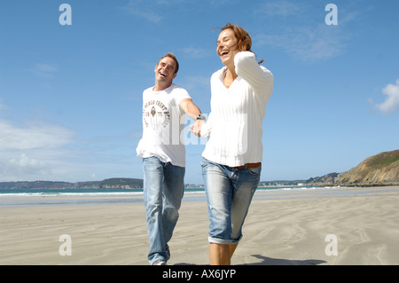 Couple running on beach and smiling Stock Photo