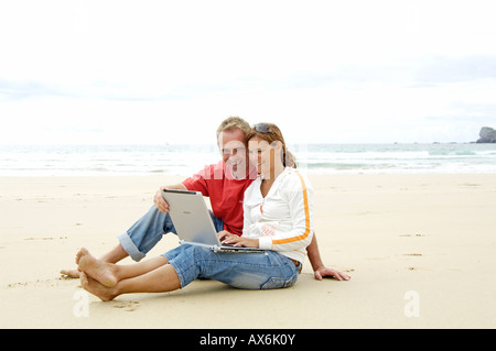 Close-up of couple using laptop on beach Stock Photo