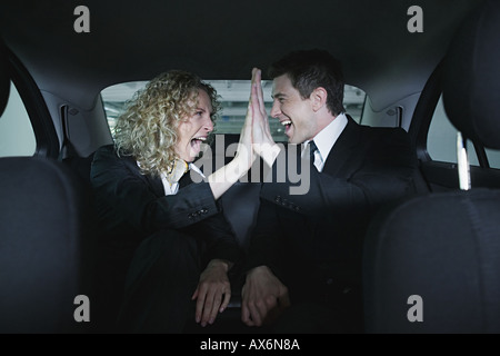 Colleagues in car doing a hi five Stock Photo