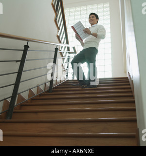 Low angle view of a businessman standing on a staircase with a file in his hand Stock Photo