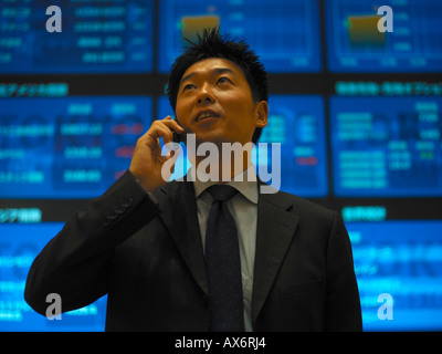 A Businessman talks on his mobile phone inside the electronic Tokyo Stock Exchange Tokyo Japan Released Stock Photo