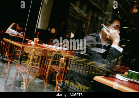 Man on mobile phone in Hong Kong sits inside the popular Pacific Coffee shop on Hollywood Road Stock Photo