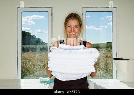Young woman holding a pile of towels Stock Photo - Alamy