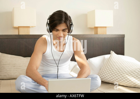 Young man with earphones sitting in front of a laptop Stock Photo